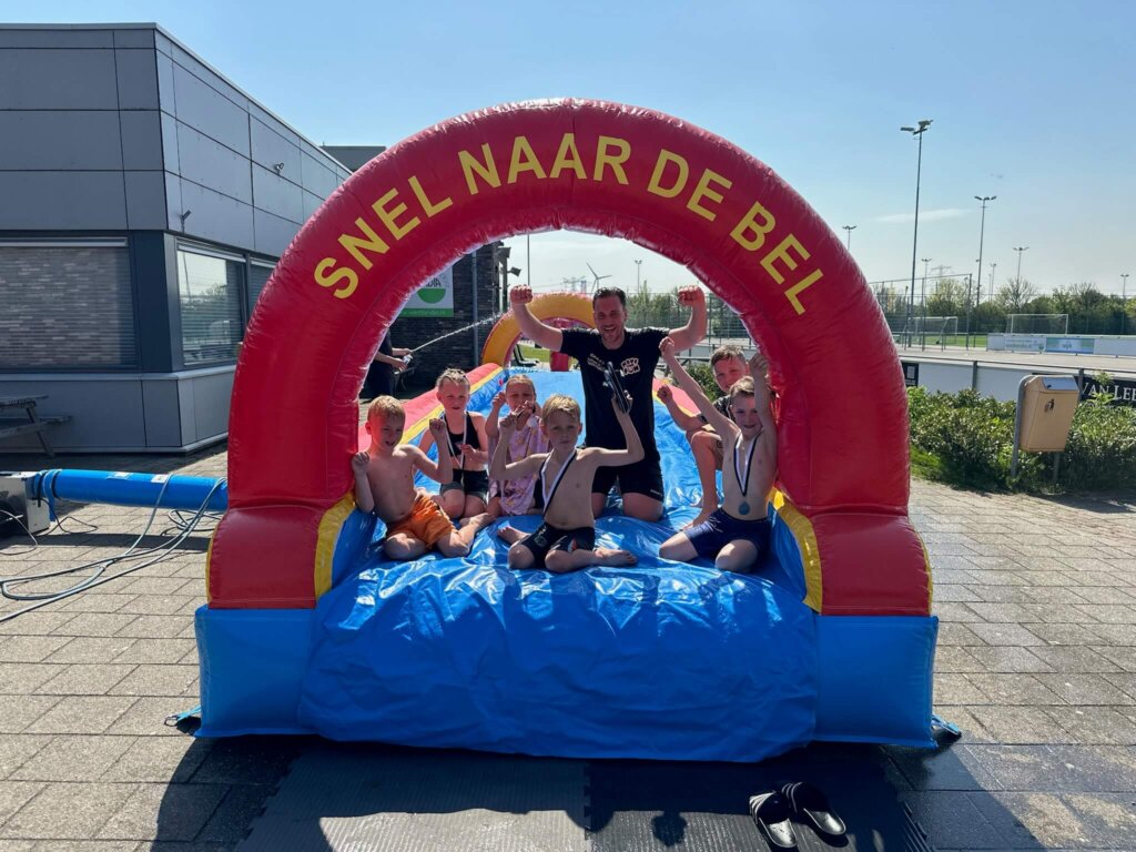 Buikschuifbaan snel naar de bel met lachende kinderen op het Move For Fun kamp in Naaldwijk