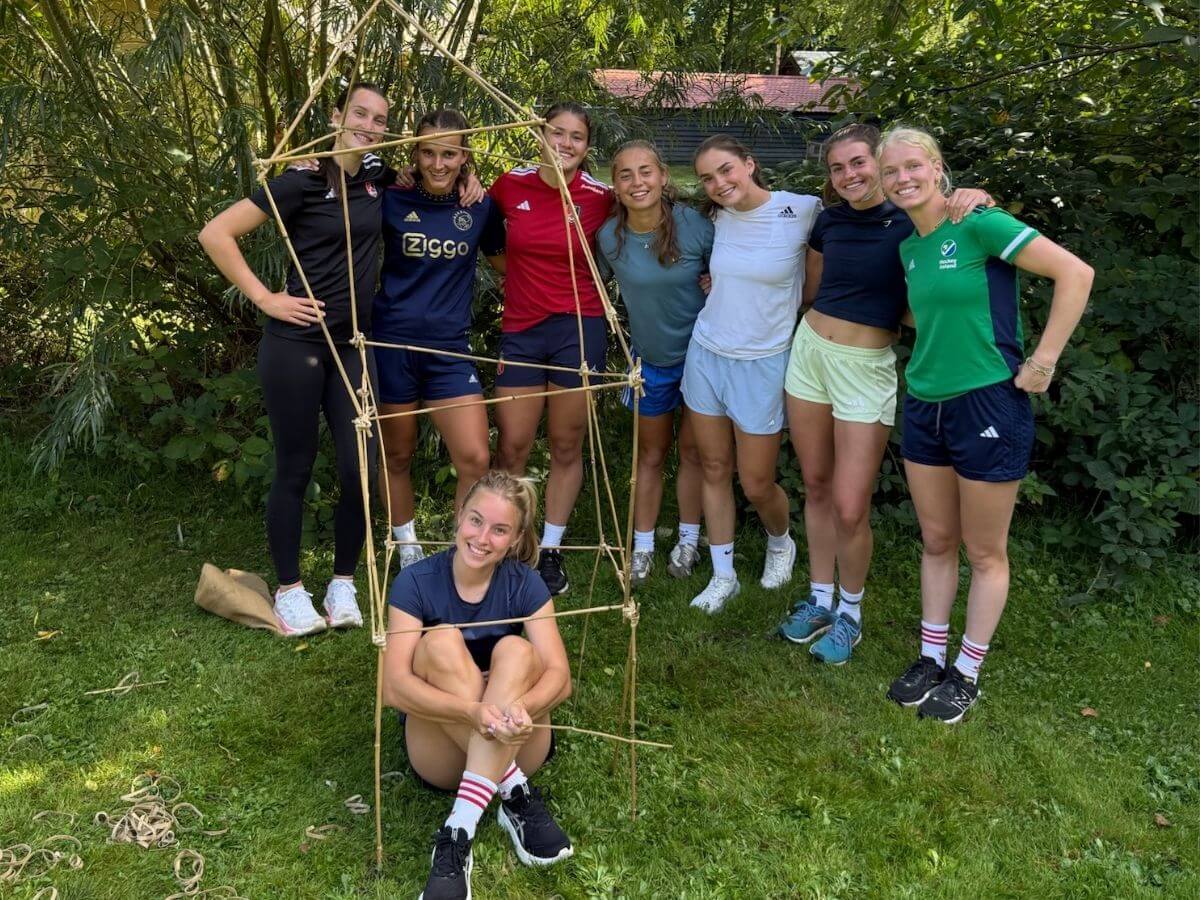 Samen bouwen en samenwerken tijdens teambuildingactiviteiten Een groep deelnemers bouwt samen een bamboeconstructie tijdens een teambuildingopdracht van Move For Fun.