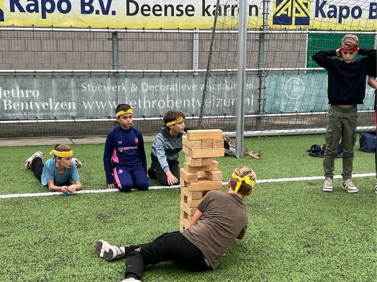 Kind probeert voorzichtig een blok uit de Mega Jenga toren te halen tijdens Expeditie Robinson feestje