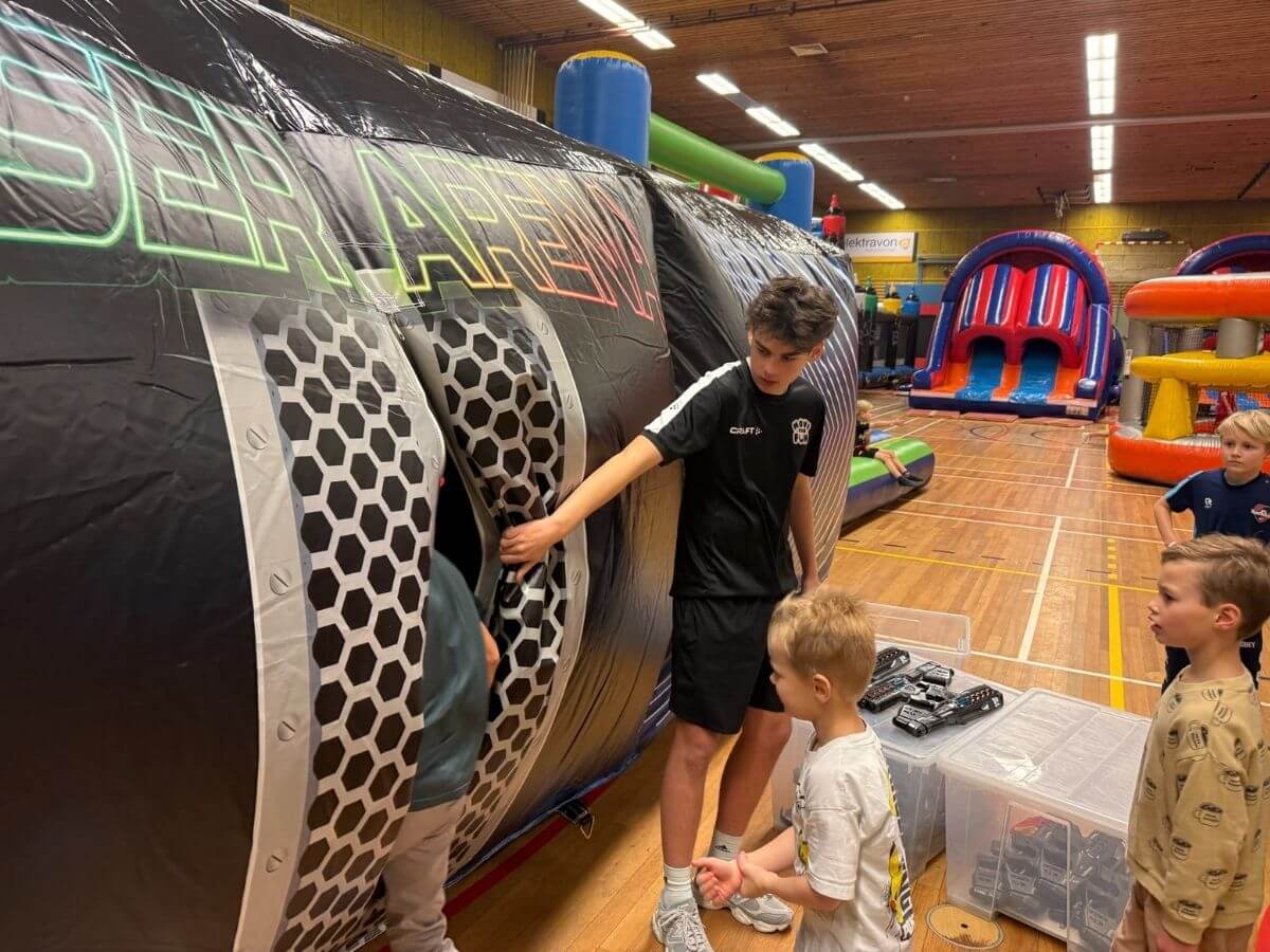 Begeleider helpt kinderen bij het betreden van de lasergame arena tijdens een sport- en speldag van Move For Fun