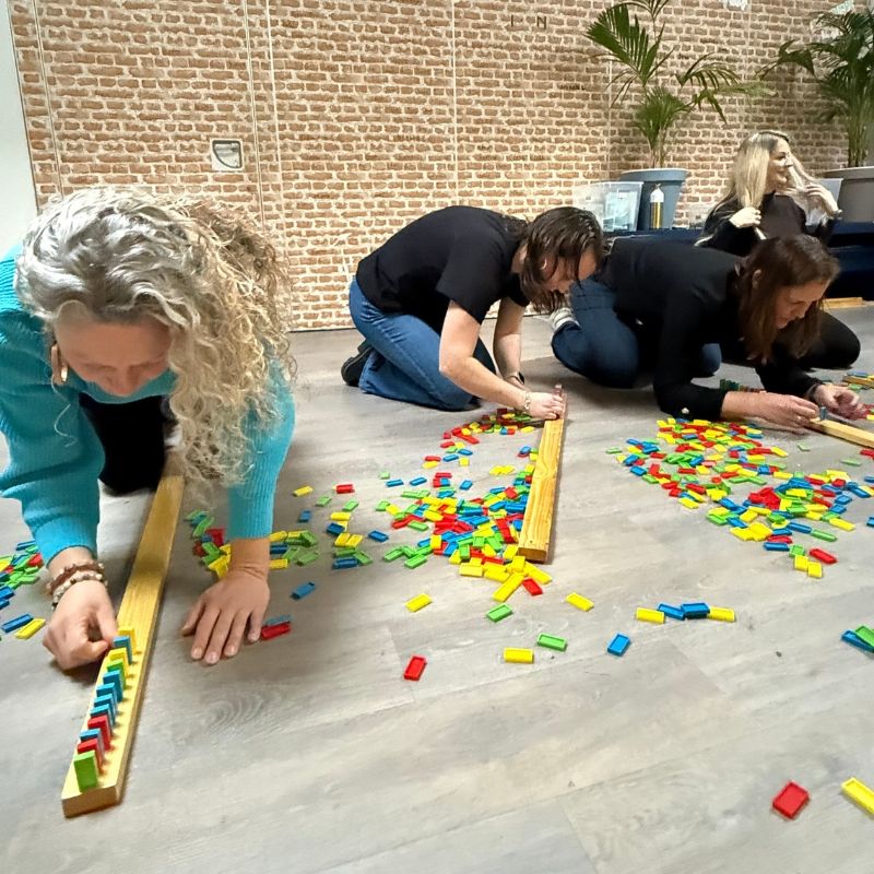 Deelnemers bouwen een dominorij tijdens het teamuitje De Alleskunner